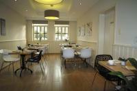 a restaurant with wooden tables and white chairs at Bed &amp; Breakfast De Kleine Magnolia in Tessenderlo