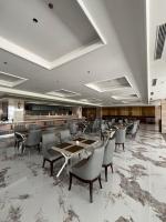 Un restaurante con mesas y sillas y un bar. en Grand Travello Hotel Bekasi, en Kedaung
