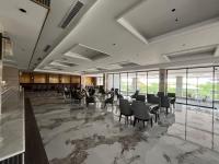 un salón de banquetes con sillas, mesas y ventanas en Grand Travello Hotel Bekasi, en Kedaung