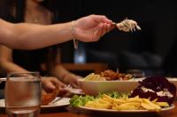 una persona comiendo comida en una mesa con un plato de comida en Asila Hills Resort, en Al Sharqiyah