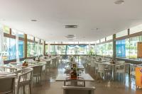 ein Restaurant mit weißen Tischen und Stühlen und Fenstern in der Unterkunft Flat no Marulhos Suites Resort - unidade C104 Térreo in Porto De Galinhas
