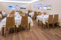 une salle à manger avec des tables blanches et des chaises en bois dans l'établissement Checkin Catalonia, à Calella