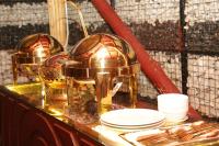 a buffet with gold plates and silverware on a table at Diamond Delight Boutique Hotels in Moshi
