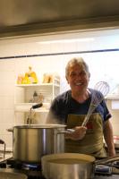 Un hombre en una cocina revolviendo una olla con un batidor. en Cascina De' Fagiolari, en Lastra a Signa