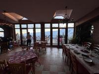 a dining room with tables and chairs and windows at Casa Leone Hotel&Restaurant in Popova Shapka