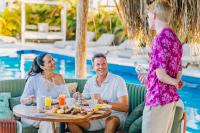 克拉伦代克Delfins Residences的一位女士正在和一位坐在桌旁用餐的男士交谈。