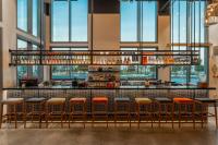 un bar con taburetes naranjas en una habitación con ventanas en Wink Hotel Tuy Hoa Beach, Unscripted by Hyatt, en Tuy Hoa