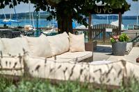 a white couch sitting on a patio near the water at See Side Hotel SEEWIRT MATTSEE in Mattsee