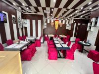 a restaurant with tables and red chairs in a room at Claridge Star Hotel in Ras al Khaimah