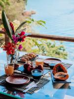 una mesa con platos de comida en una mesa cerca del agua en Glamping Sitio das Tartarugas, en Praia da Longa