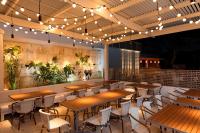 Un restaurante con mesas y sillas de madera y luces. en The Sarasota Modern, a Tribute Portfolio Hotel, en Sarasota