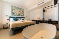 Baño con bañera junto a una cama con pintura en B&amp;B Le Suites di Costanza, en Cefalú
