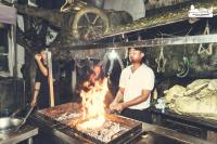 a man cooking food on a grill with a fire at Chintan Chautari in Itahari