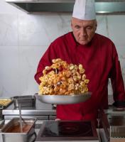 een chef-kok met een bord eten in de keuken bij Sunshine Village Hotel in Chersonissos