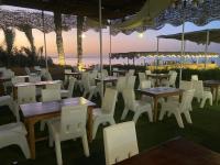 ファイユームにあるJazirat Alqarn Hostelのテーブルと白い椅子が備わる海の景色を望むレストラン