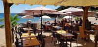personnes assises à des tables sur la plage sous des parasols dans l'établissement Les Oliviers de l'Esterel, à Saint-Raphaël