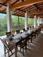 una larga mesa de madera y sillas en un patio en Kitulgala Ebony Riverside Resort, en Kitulgala