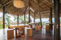 een restaurant met tafels en stoelen en een rieten dak bij RoomQuest THEVA Resort Koh Samui in Koh Samui 