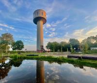 una torre con un reflejo en un cuerpo de agua en Watertorenhotel Wadhoog, en Sint Jacobiparochie