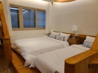 zwei Betten in einem Zimmer mit zwei Fenstern in der Unterkunft Hanok stay Mokhyang in Gyeongju