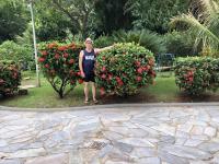 a woman standing in front of a bush of roses at Golden Dolphin Express in Caldas Novas