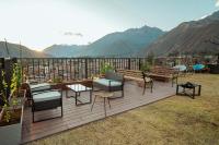 Una terraza con sillas y mesas con montañas al fondo. en Hotel California Urubamba, en Urubamba