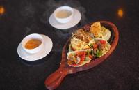 een tafel met een bord eten en twee kopjes soep bij Vanashraya Corbett Resort in Rāmnagar