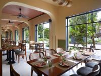 a restaurant with tables and chairs and large windows at Radha House Siolim A Boutique Hotel in Oxel