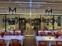 een restaurant met witte tafels en rode stoelen en de woorden mlection bij Hotel Ristorante Milton in Varazze