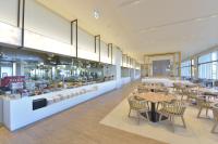 Un restaurante con mesas y sillas y una cocina. en The Orion Hotel Motobu Resort & Spa, en Motobu