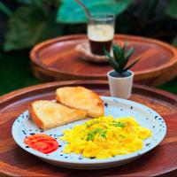 a plate of scrambled eggs and toast on a table at Omah Apartments in Pune