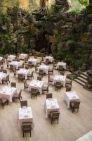 Un restaurante con mesas y sillas y una pared de piedra. en Clarion Suites Guatemala City, en Guatemala