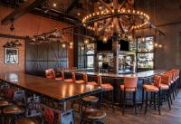 um bar com mesas e cadeiras de madeira num restaurante em The Craftsman Inn & Suites em Fayetteville