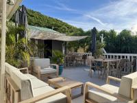 an outdoor patio with tables and chairs and a table at Koho SXM - ex Hevea Hotel in Grand Case