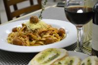 Um prato de massa com almôndegas e queijo e um copo de vinho. em Hotel Genova Centro em Barranquilla