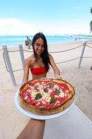 a woman holding a large pizza on the beach at Boca Beach Residence hotel in Boca Chica