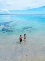 a man and woman walking in the water on a beach at Boca Beach Residence hotel in Boca Chica
