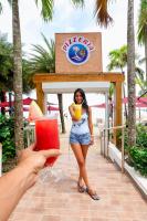 a woman holding a drink in front of a sign at Boca Beach Residence hotel in Boca Chica