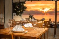 a wooden table with glasses and napkins on it with a sunset at The MAVERICK SURF AND DIVE BOUTIQUE HOTEL - Book 10 Nights and get 1 Free Night - Free Speed Boat Service - Kids Stay Free in Laamu