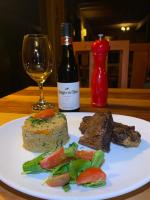 a plate with meat and vegetables and a bottle of wine at Lodge Cumbres de Chiloe in Castro
