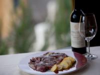 Un plato de carne y una botella de vino en una mesa en Hotel Rural El Yantar de Gredos, en San Martín del Pimpollar