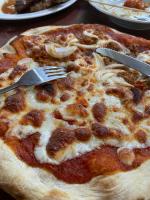 een pizza met een vork en een mes op tafel bij Sunmoon Beach Resort Likupang Timur in Pulau Mogogimbun