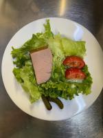 una placa de lechuga y tomates sobre una mesa en LOGIS Hôtel Restaurant La Chaumière, en Marseillan