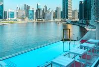 a swimming pool on the edge of a river with a city at Canal Central Hotel Business Bay in Dubai