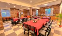 un restaurante con mesas y sillas rojas y ventanas en WANDER THRIVES INN By Ads Manali, en Manali