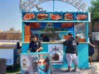 dos hombres parados en un puesto de comida con una pizza en Elite apartment private beach Holiday Chalet Free WIFI, en Hurghada