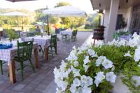 eine Terrasse mit Tischen, Stühlen und weißen Blumen in der Unterkunft Agriturismo Mazzeracca in Bassano del Grappa