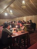 a group of people sitting at a table in a tent at Touareg Desert Camp Erg Chigaga in El Gouera