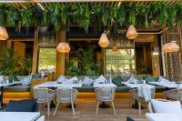 a restaurant with white tables and chairs and plants at Novos Luxury Suites in Bucharest