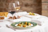 Una mesa con un plato de comida y una copa de vino. en Marchese Del Grillo, en Fabriano